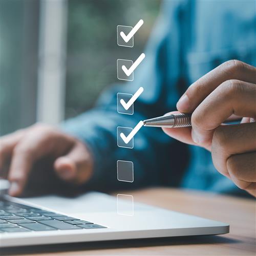 A person completing a floating checklist above their laptop.