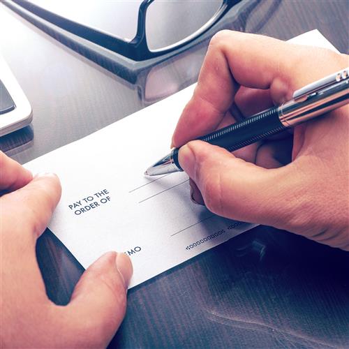 A hand signing a bank guarantee cheque
